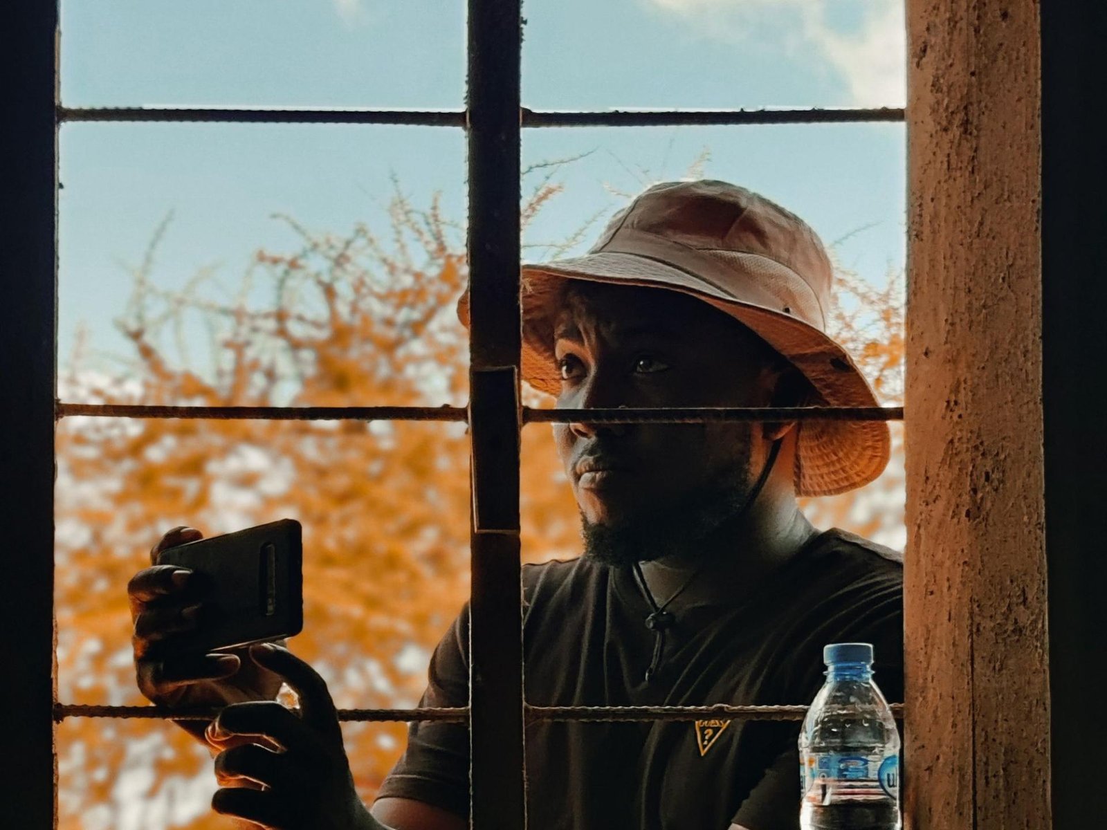 Man using a smartphone at a window in Chamwino, Tanzania