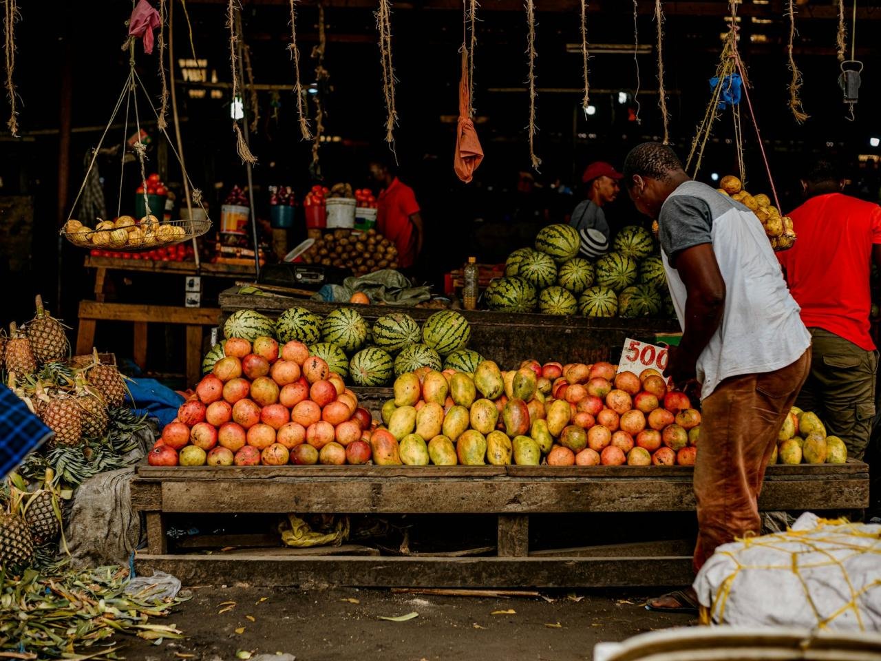 Market trader with prices displayed on produce